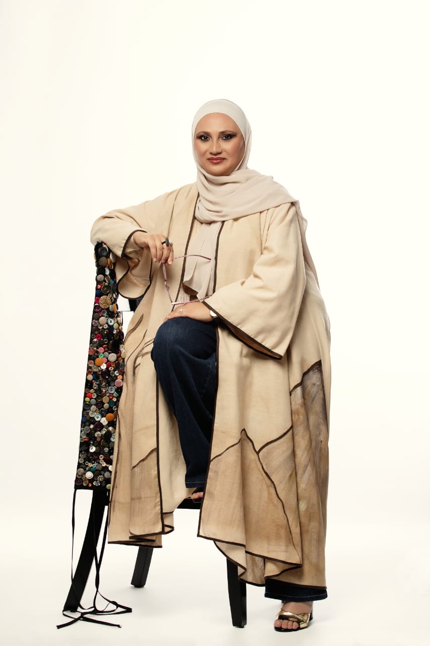 Woman wearing a beige hijab and coat on a white background