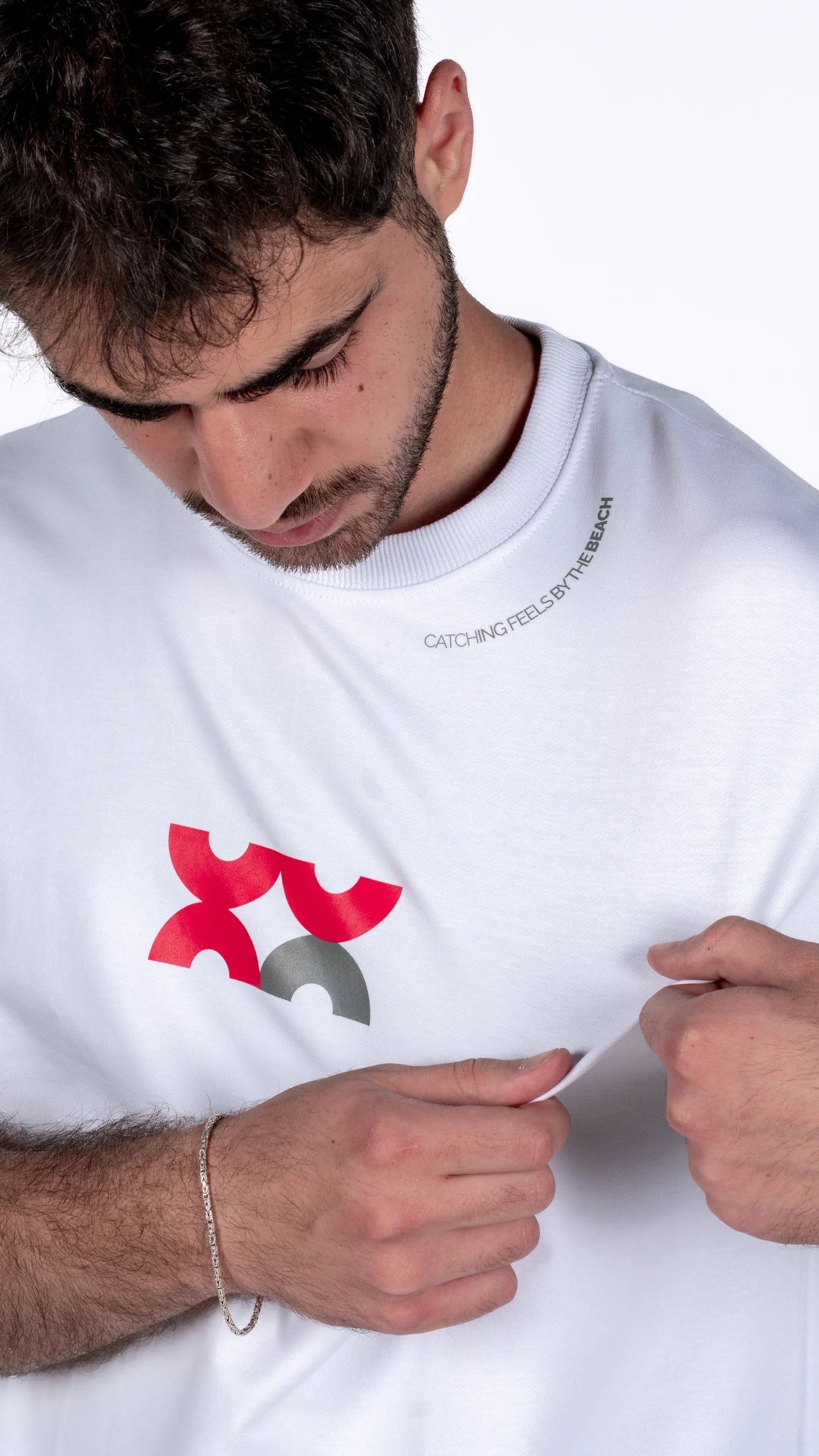 Person wearing a white t-shirt with a red and gray logo on a white background