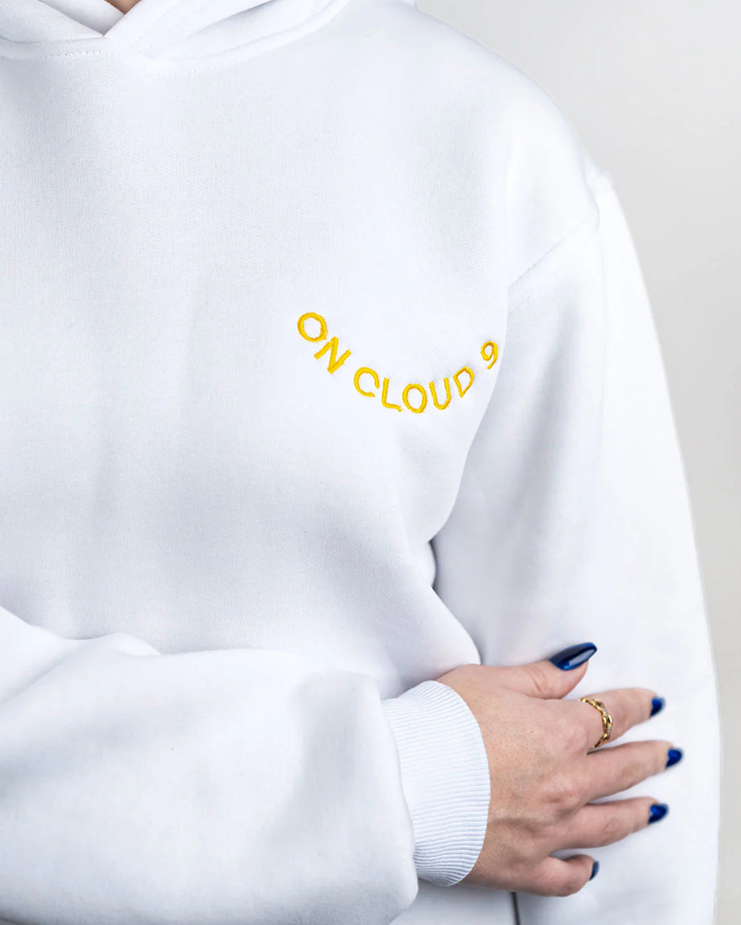 White sweatshirt with 'ON CLOUD 9' text in yellow on a plain background