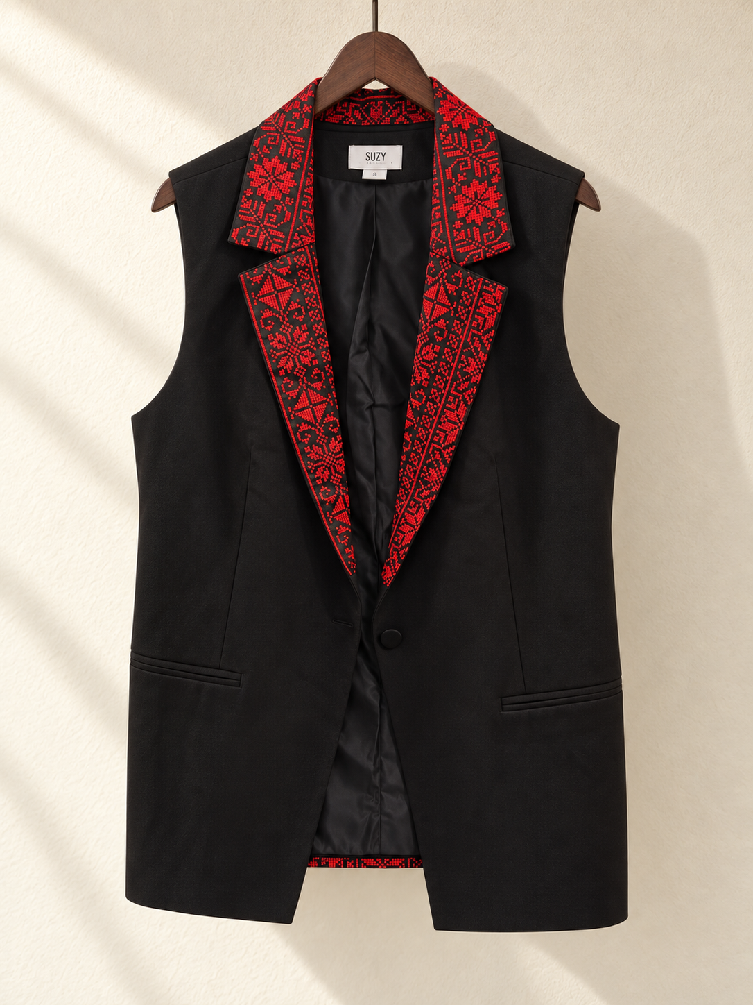 Black Sleeveless Blazer Vest with Red Embroidered Collar — front view on wooden hanger