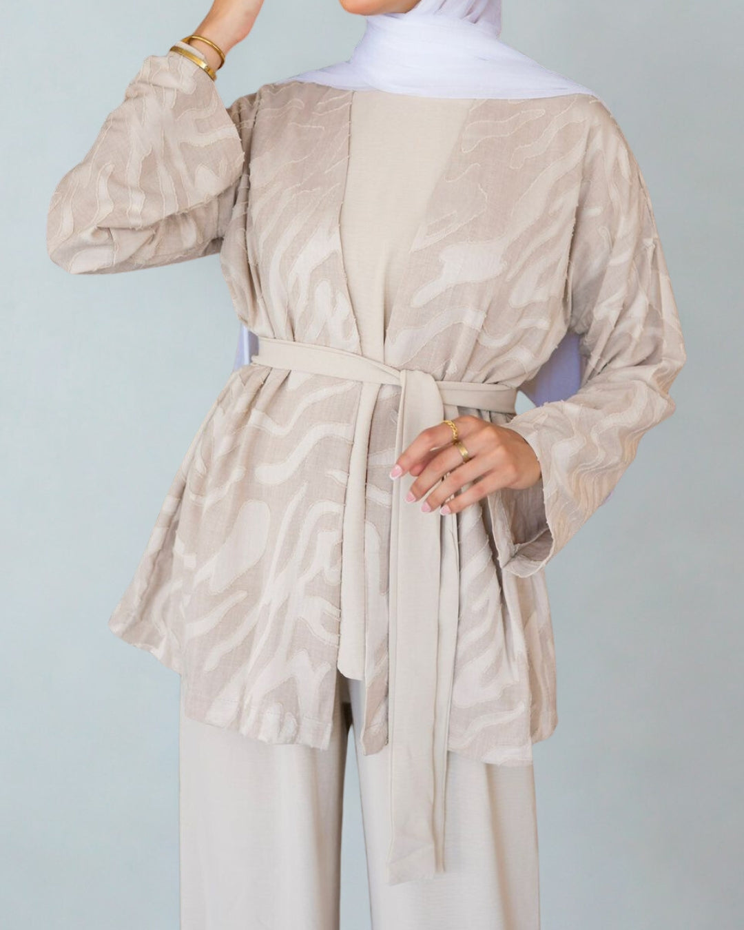 Beige outfit with a belt on a plain background
