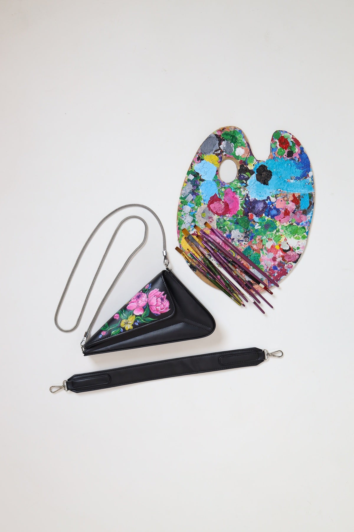Floral-patterned clutch bag with a matching floral paint palette on a white background
