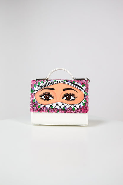 Handbag with a face design and floral accents on a white background