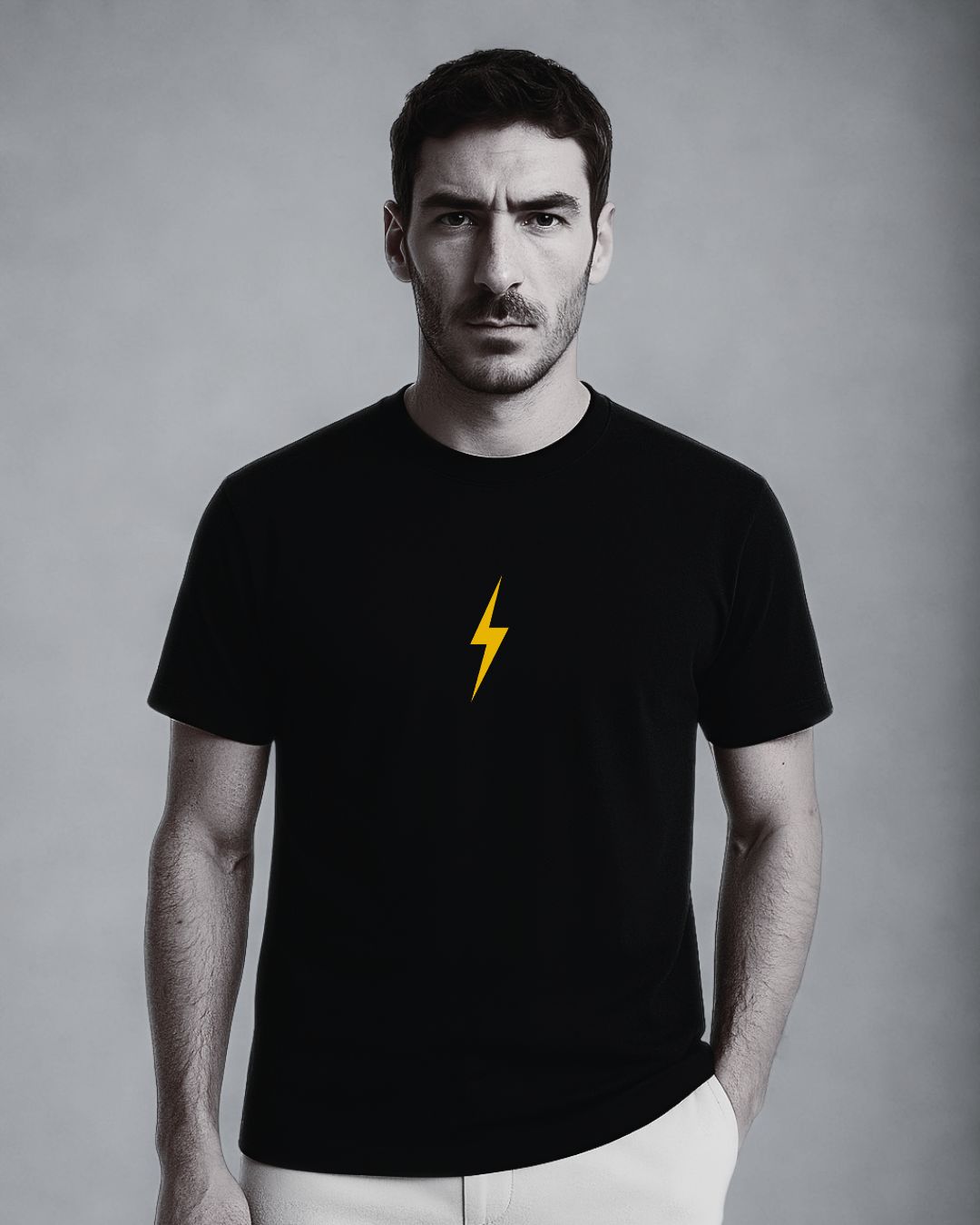 Man wearing a black t-shirt with a yellow lightning bolt on a gray background