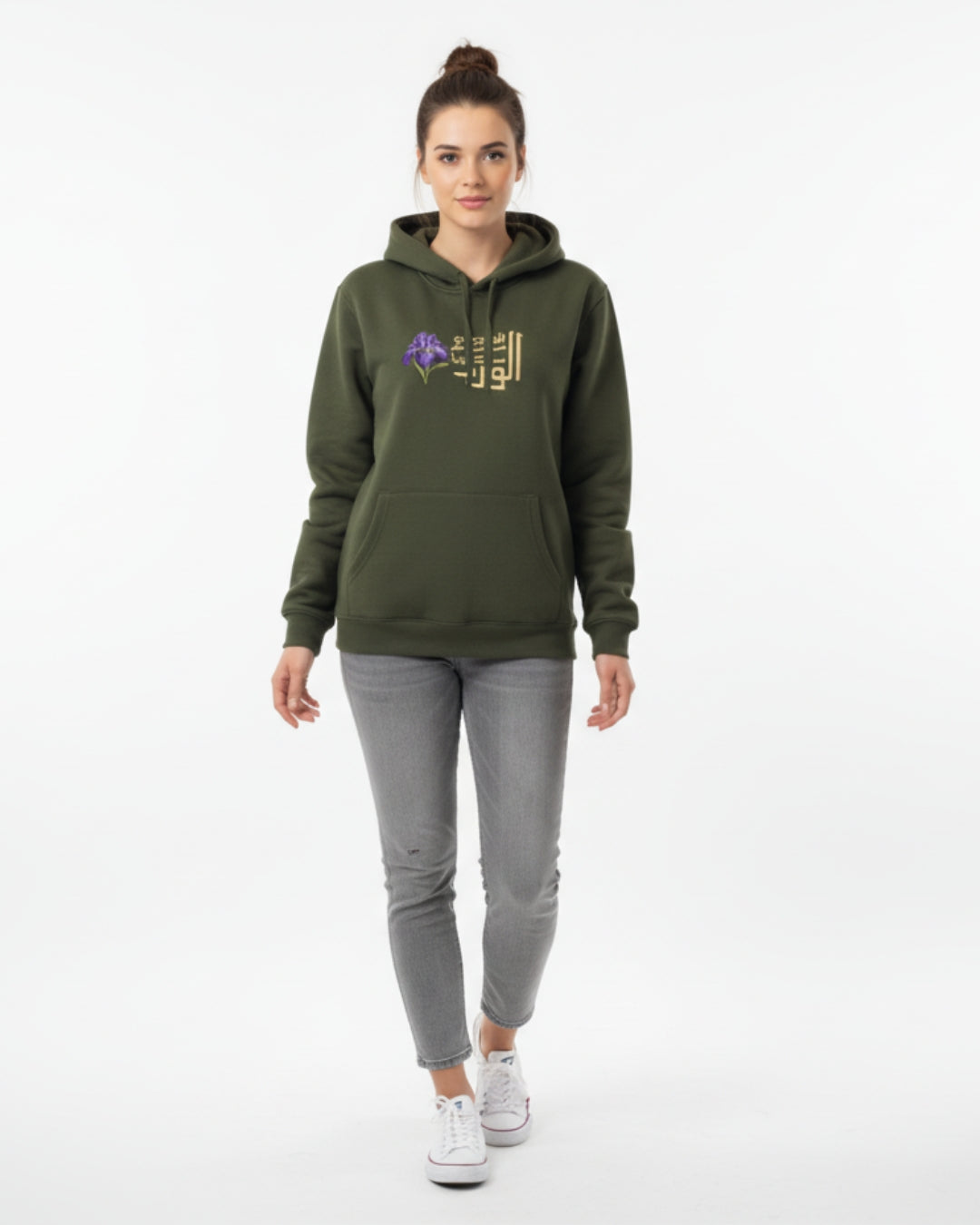 Woman wearing a green hoodie with a logo and gray pants on a white background