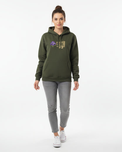 Woman wearing a green hoodie with a logo and gray pants on a white background