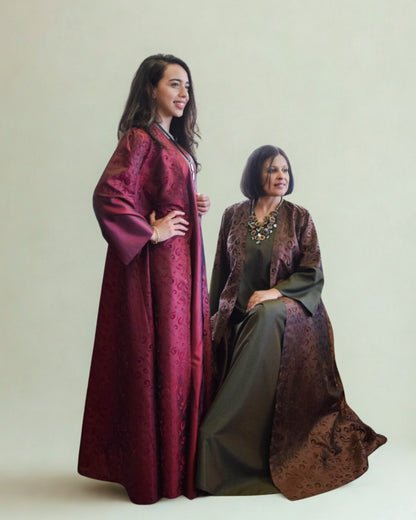 Two women wearing long, patterned dresses against a plain background