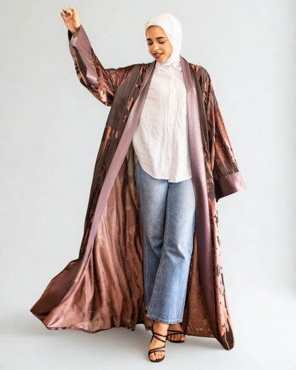 Woman wearing a long brown coat over a white top and blue jeans on a white background