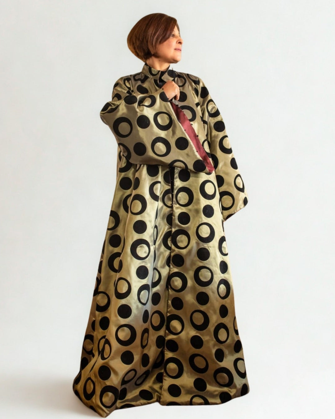 Woman wearing a gold dress with black circular patterns on a white background