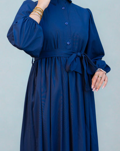 Navy blue dress with a belt on a plain background