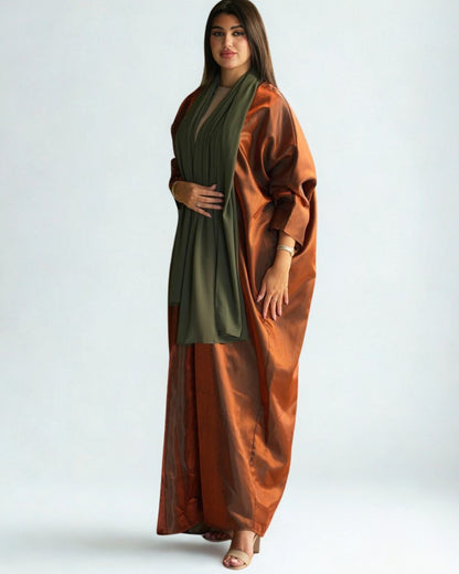 Woman wearing a long rust-colored dress with a green scarf on a white background
