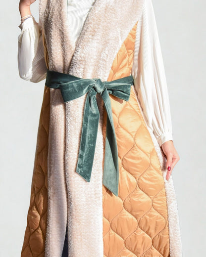 Long quilted coat with a green ribbon on a plain background