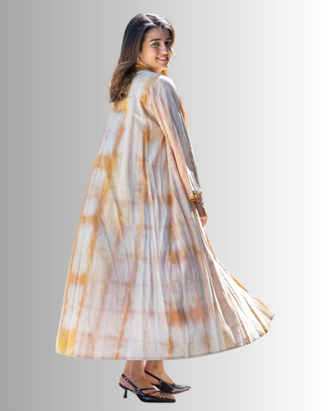 Woman wearing a long, tie-dye dress with a neutral background