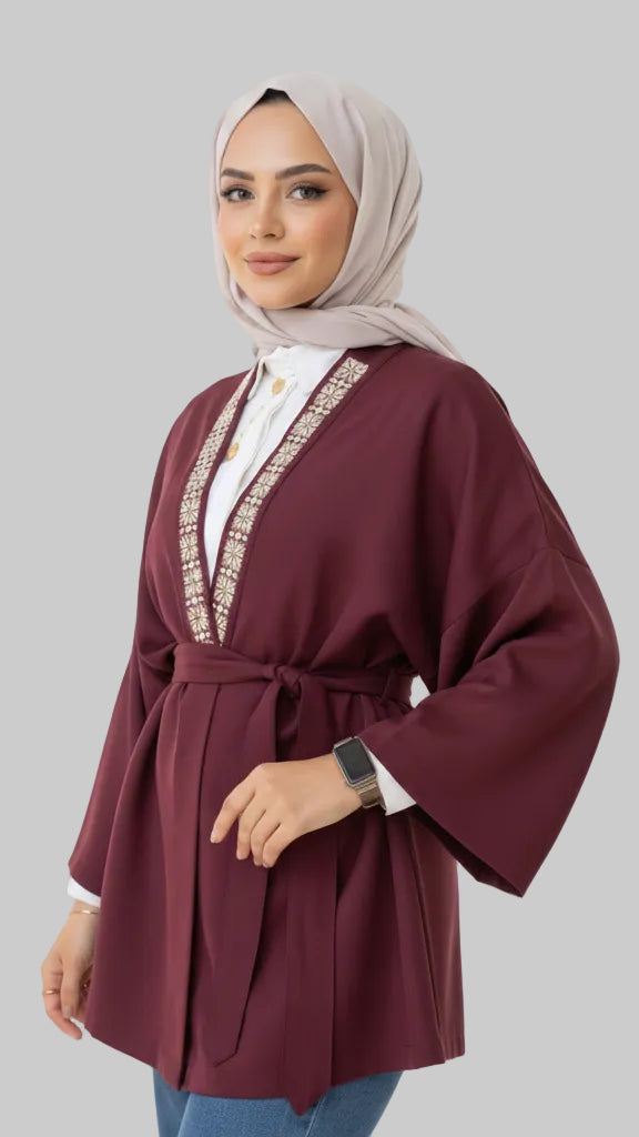 Woman wearing a burgundy abaya with white embroidery on a white background