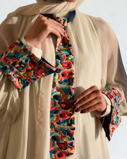Colorful patterned scarf being held by a person wearing a beige outfit.
