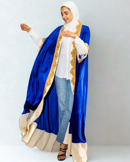 Woman wearing a blue and gold abaya with a white hijab on a light gray background