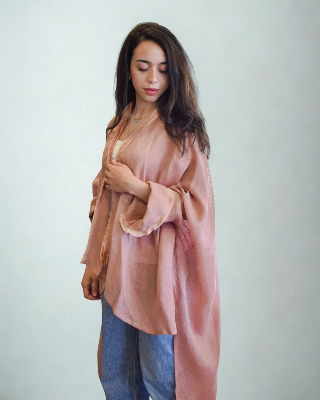 Woman wearing a long, light pink garment against a plain background