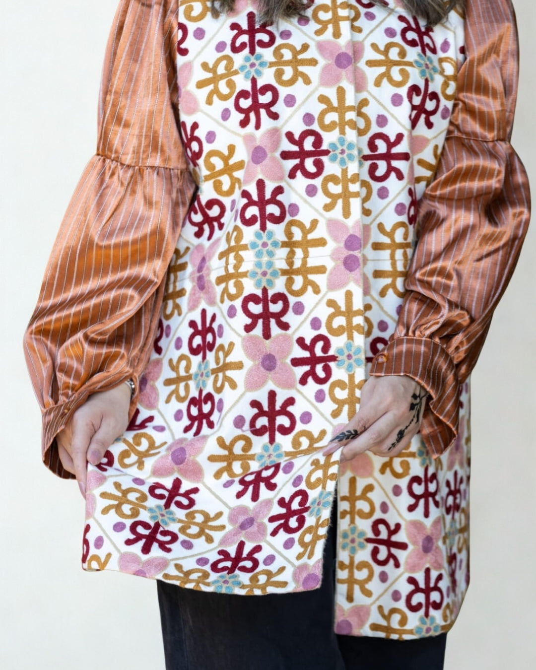 Person wearing a patterned shirt with long sleeves and a white background