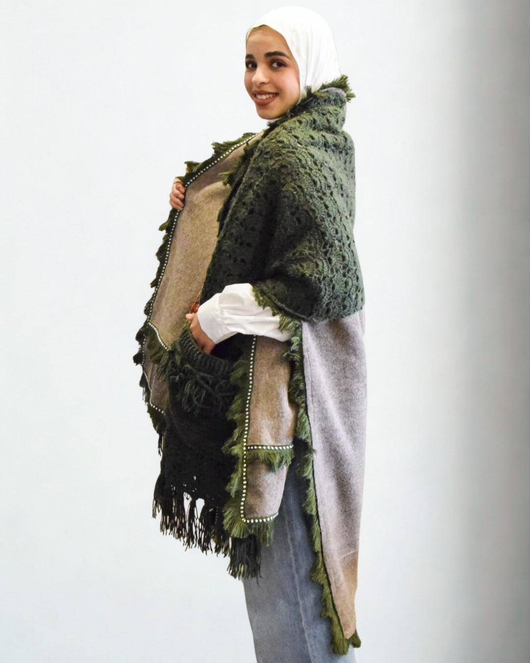 Woman wearing a green textured shawl with fringe on a white background