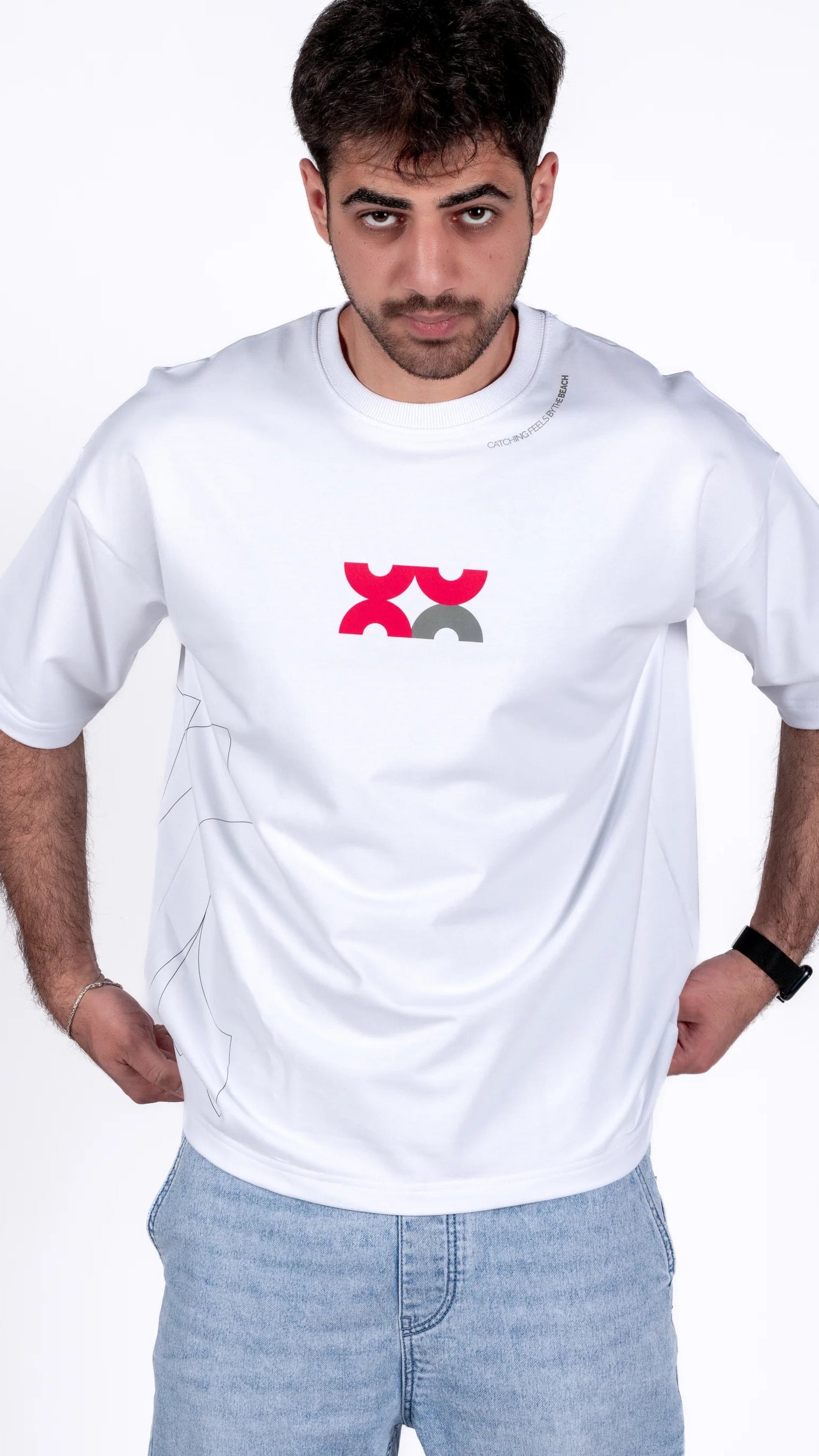 Man wearing a white t-shirt with a red and black logo on a plain background