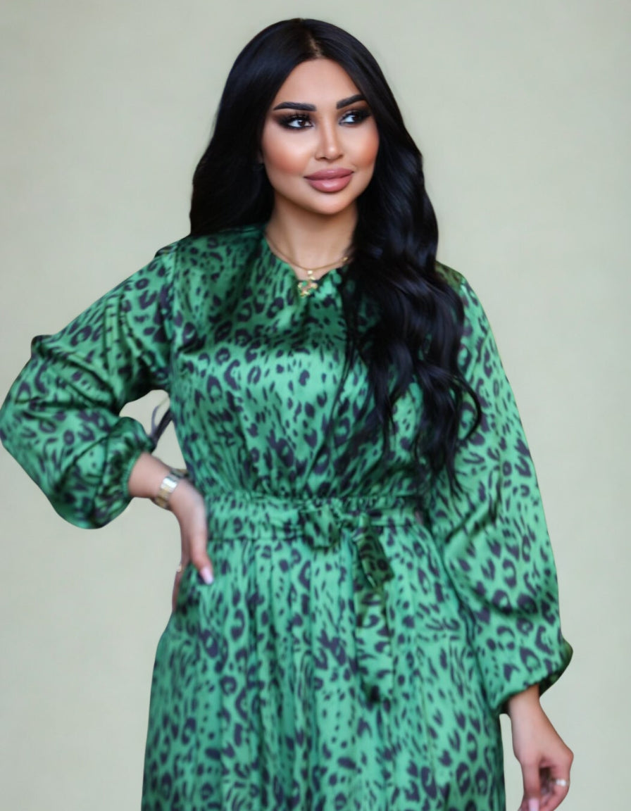 Woman wearing a green leopard print dress against a plain background