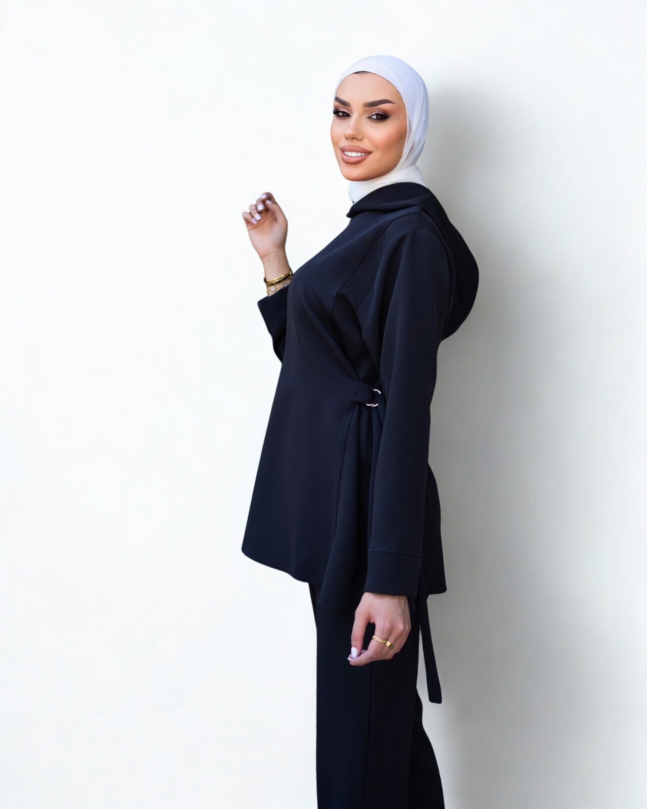 Woman wearing a navy abaya and white hijab against a white background