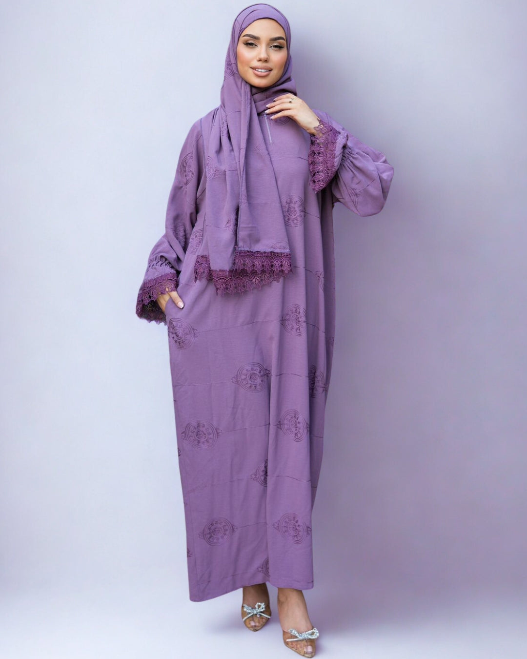 Woman wearing a purple traditional outfit with a matching hijab on a white background