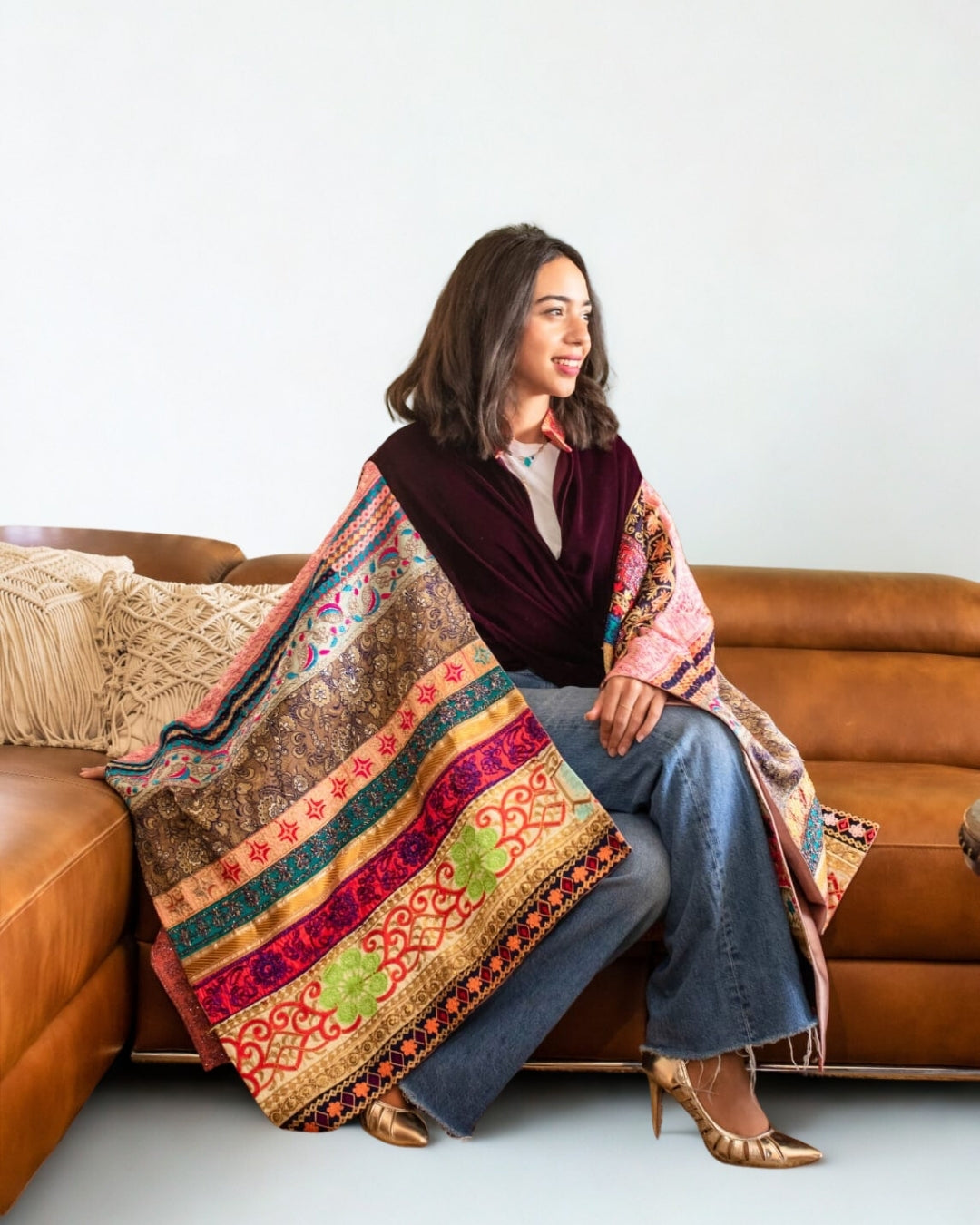 Woman sitting on a couch with a colorful patterned blanket draped over her