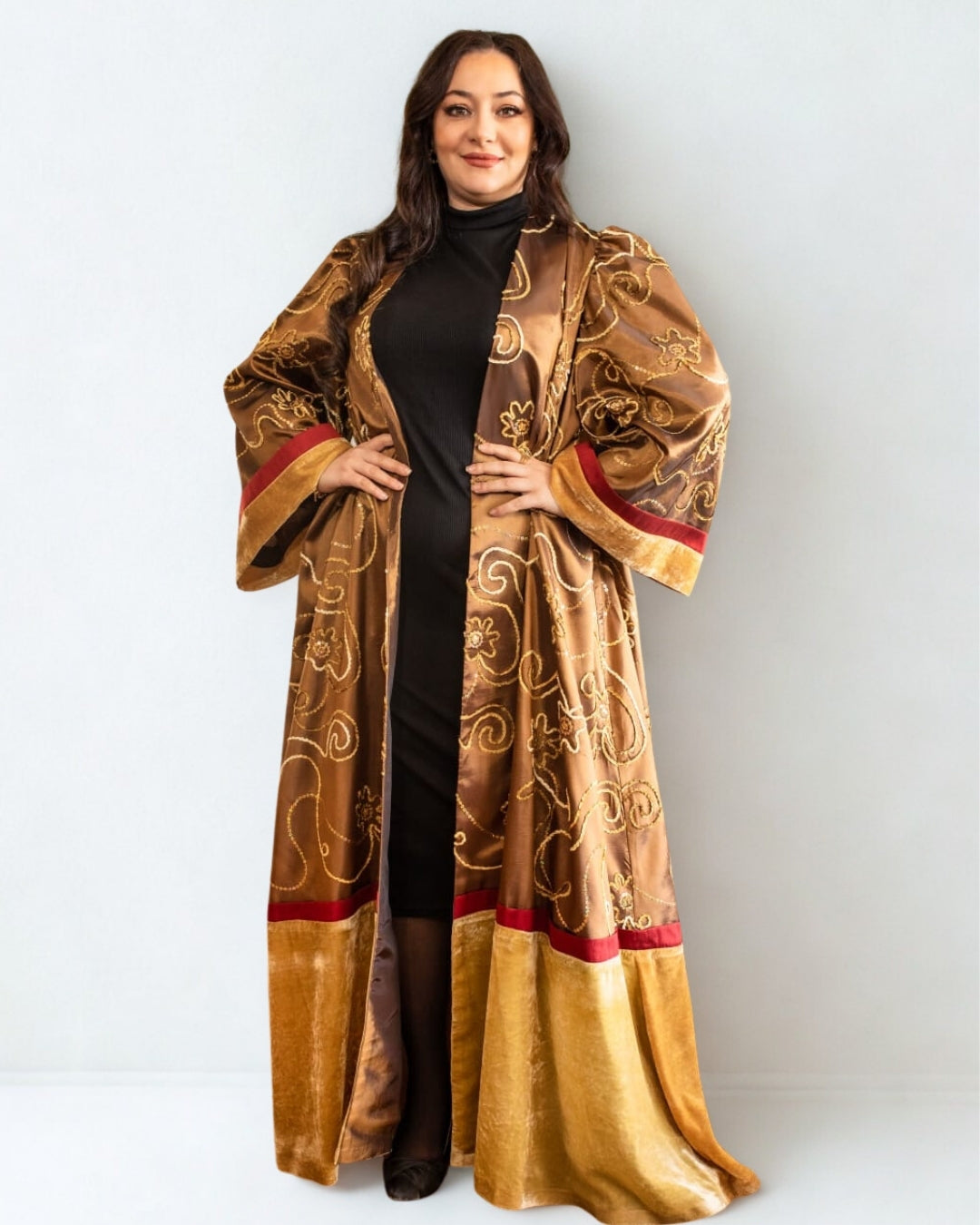 Woman wearing a long, ornate gold and red coat against a white background