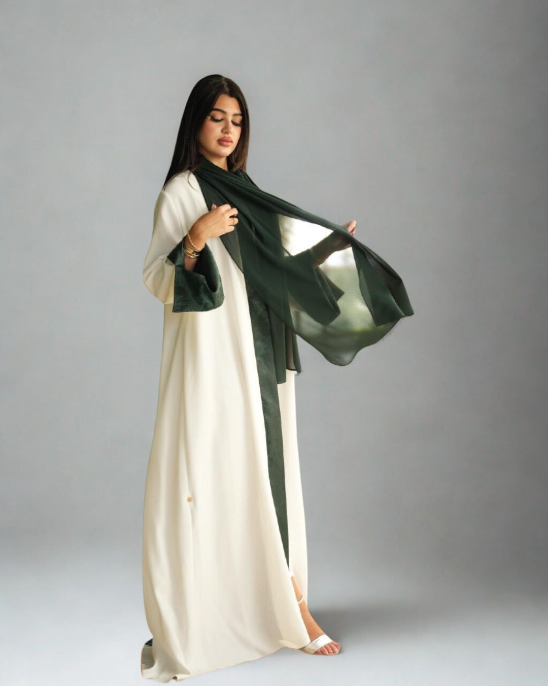 Woman wearing a white dress with a green scarf against a gray background