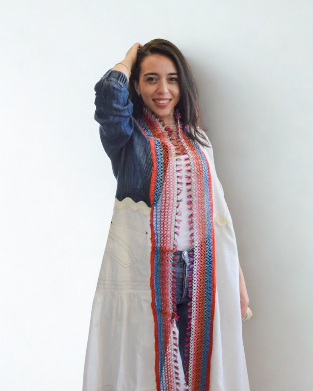 Woman wearing a colorful scarf and denim jacket against a white background