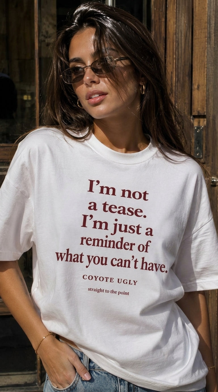 A woman wearing a white graphic t-shirt with a dark red quote printed on the front, paired with blue jeans, standing in front of a rustic wooden door.