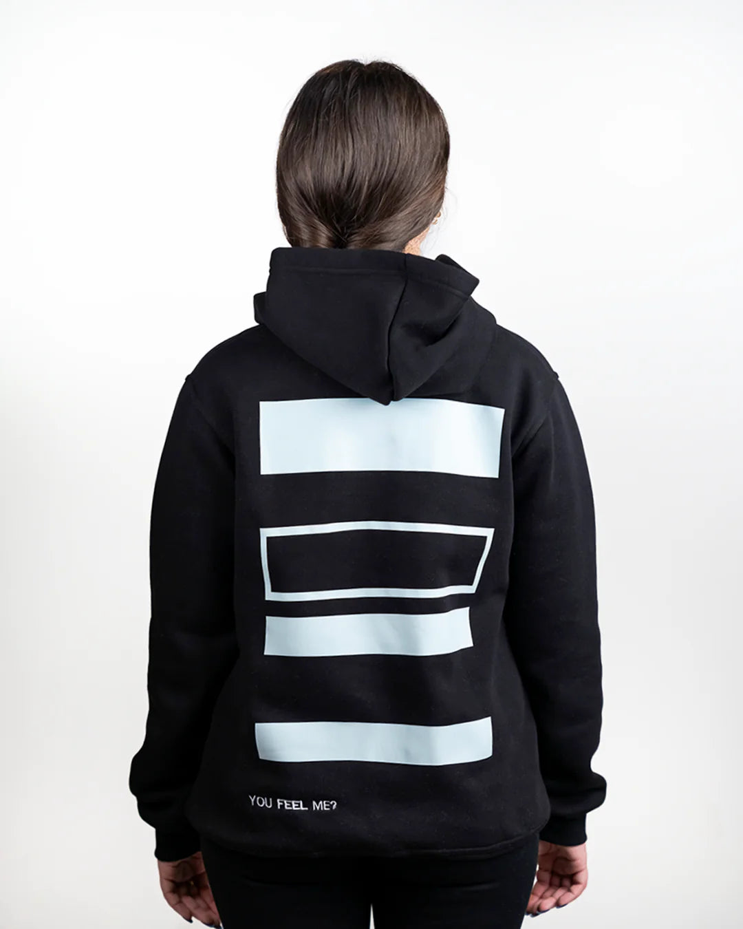 Person wearing a black hoodie with light blue geometric patterns on the back against a white background