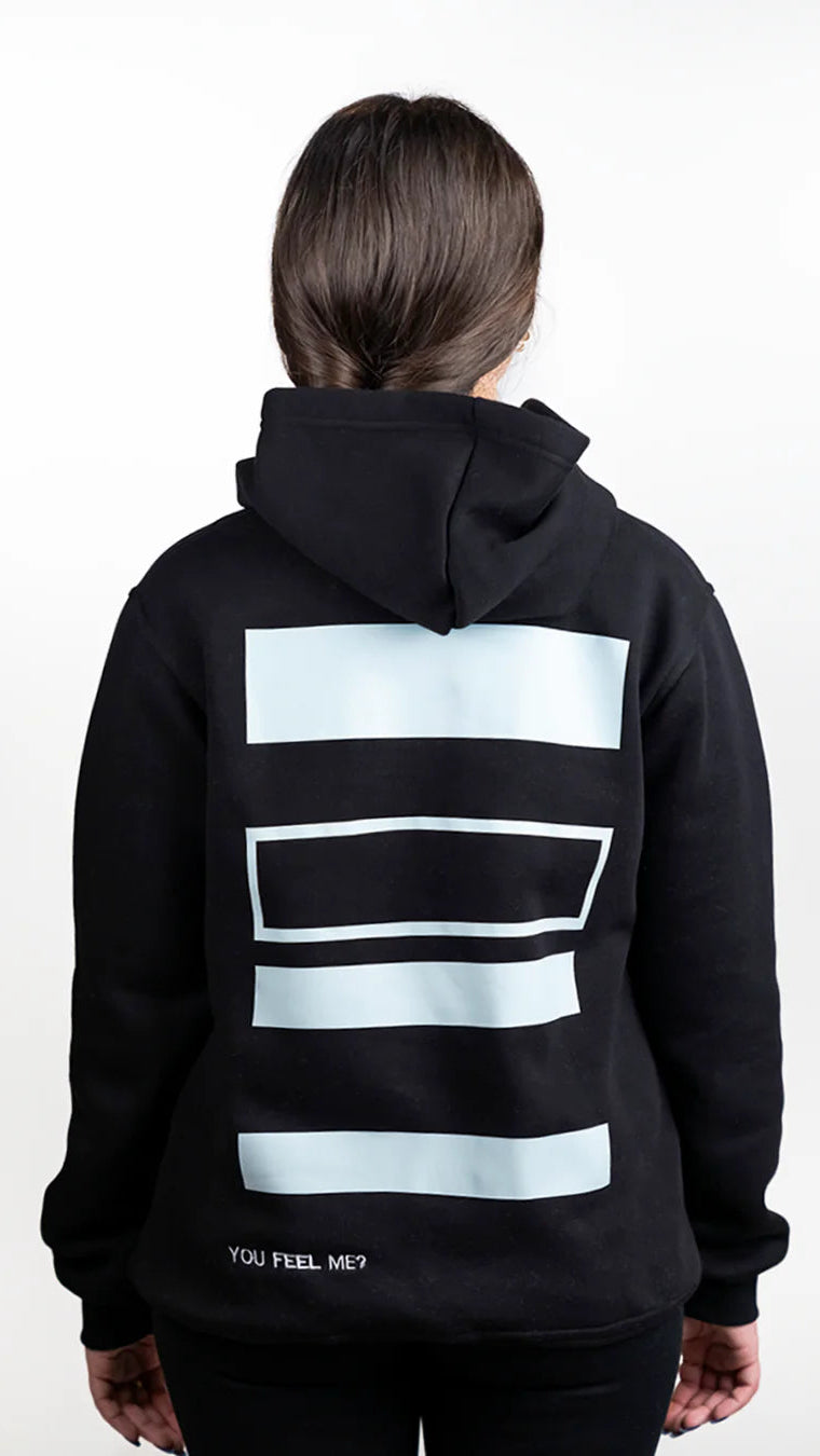 Person wearing a black hoodie with light blue geometric patterns on the back against a white background