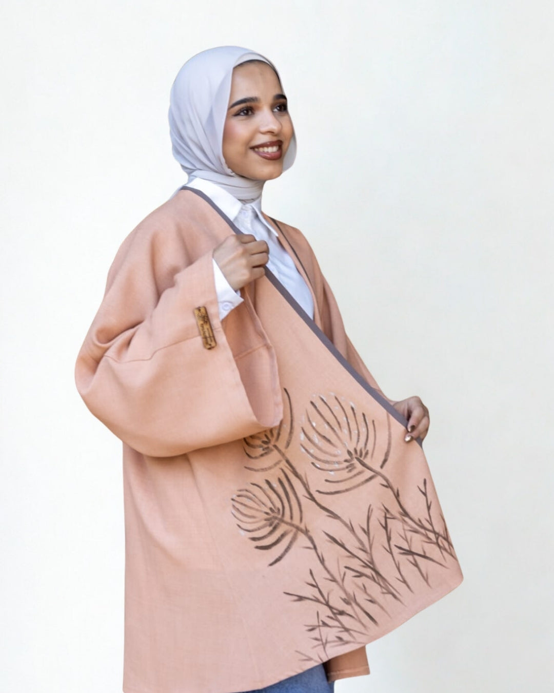 Woman holding a beige bag with leaf patterns against a white background