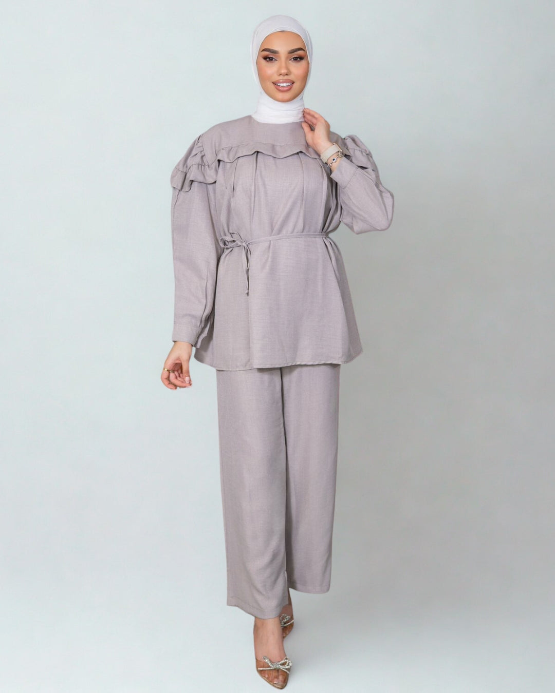 Woman wearing a gray outfit with a matching hijab on a white background