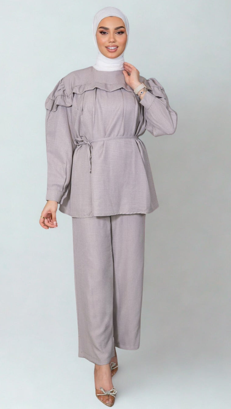 Woman wearing a gray outfit with a matching hijab on a white background