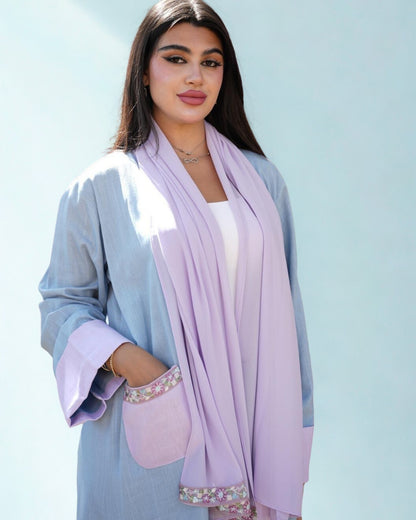 Woman wearing a light blue outfit with a lavender scarf against a light blue background