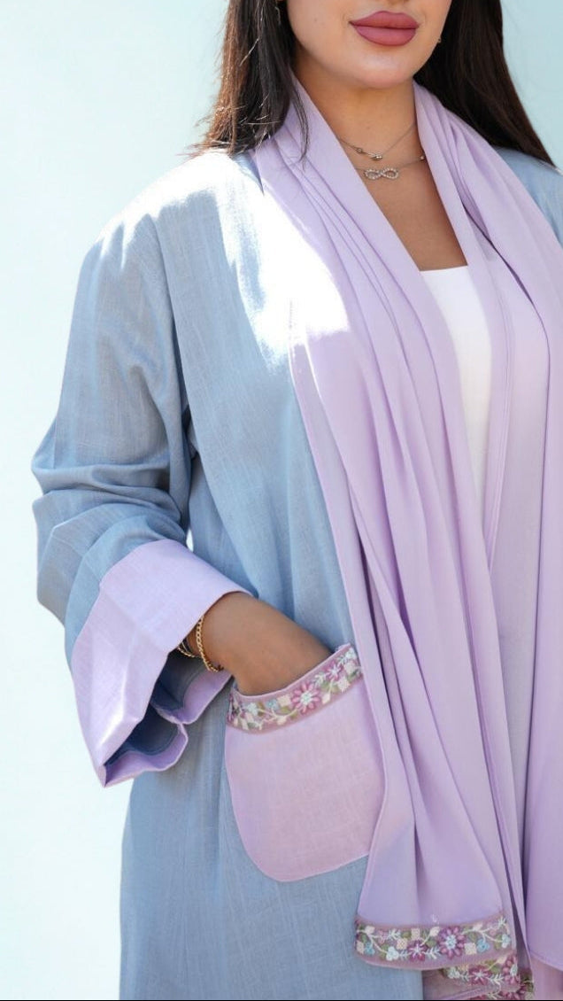 Woman wearing a light blue outfit with a lavender scarf against a light blue background