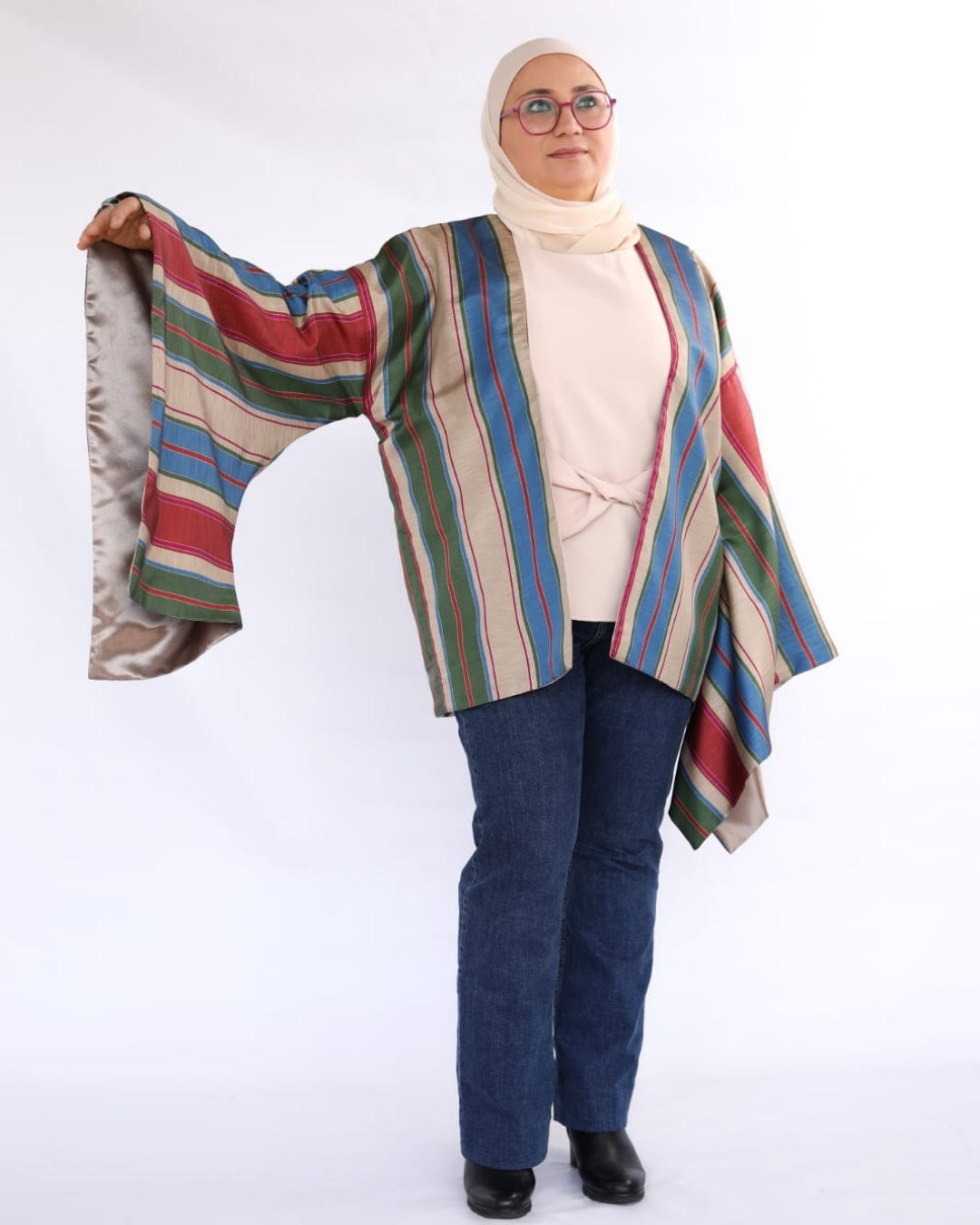 Woman wearing a colorful striped jacket over a beige hijab on a white background