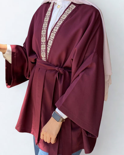 Maroon robe with intricate white embroidery on a plain background