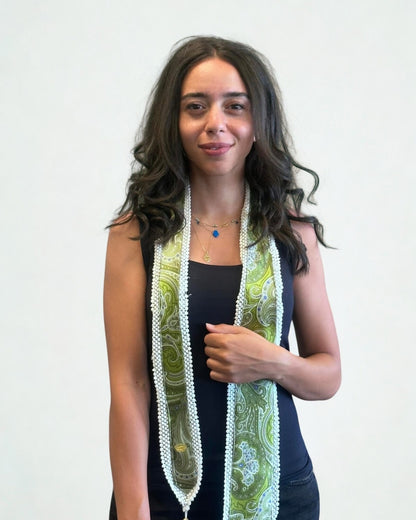 Woman wearing a long, patterned scarf against a plain background
