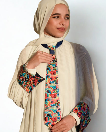 Woman wearing a beige hijab and colorful outfit against a white background