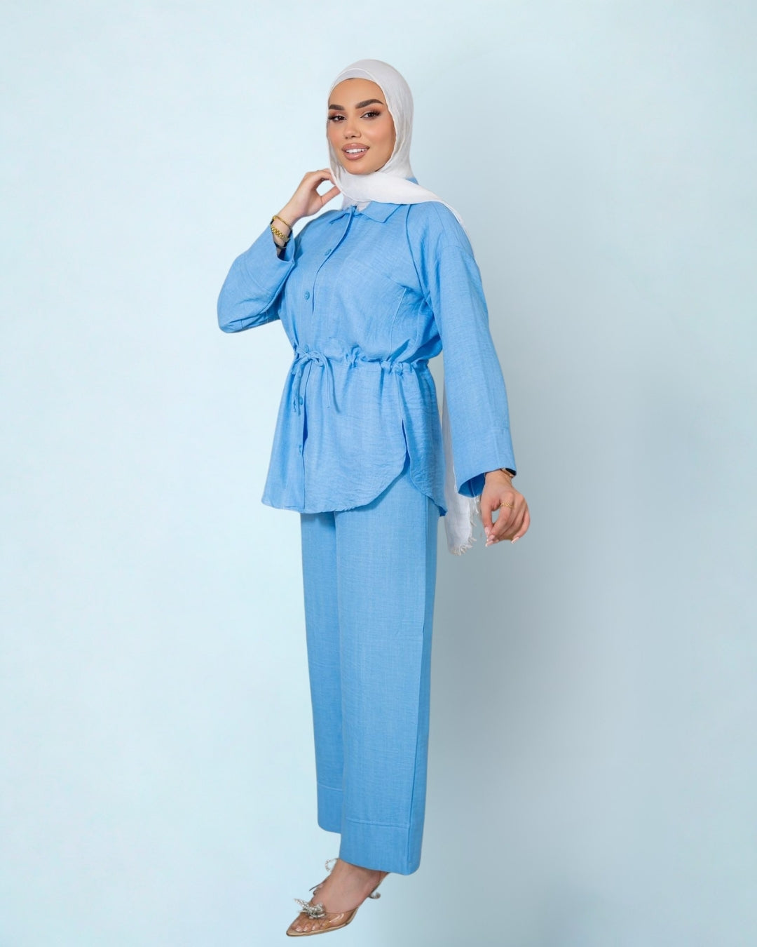 Woman wearing a light blue outfit with a matching hijab on a light gray background