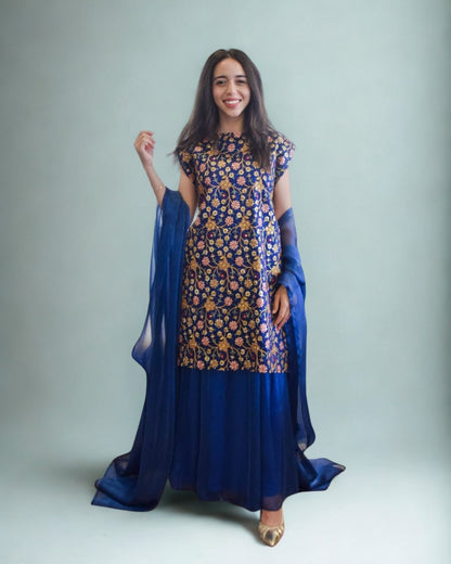 Woman wearing a blue floral dress with a matching dupatta against a plain background