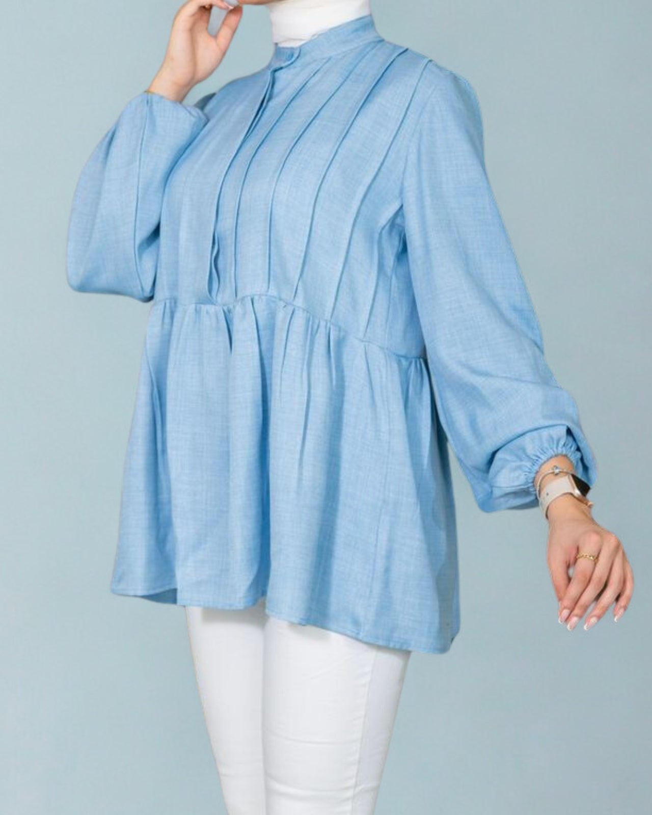 Light blue blouse worn by a person on a gray background