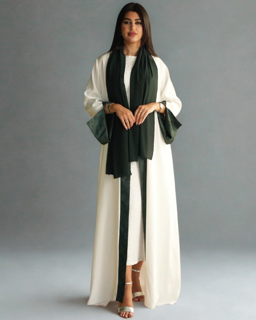 Woman wearing a long white dress with green accents against a gray background