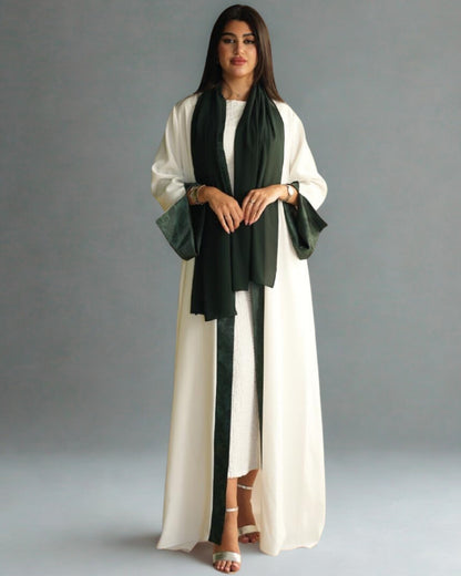 Woman wearing a long white dress with green accents against a gray background