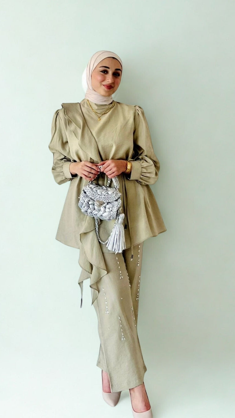 Woman wearing a beige traditional outfit with a headscarf against a light background