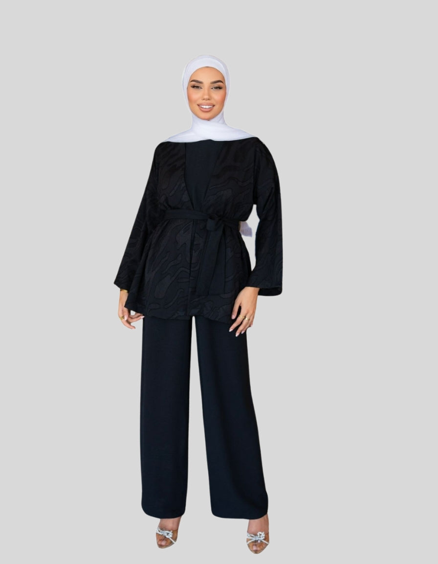 Woman wearing a black outfit with a white hijab on a gray background